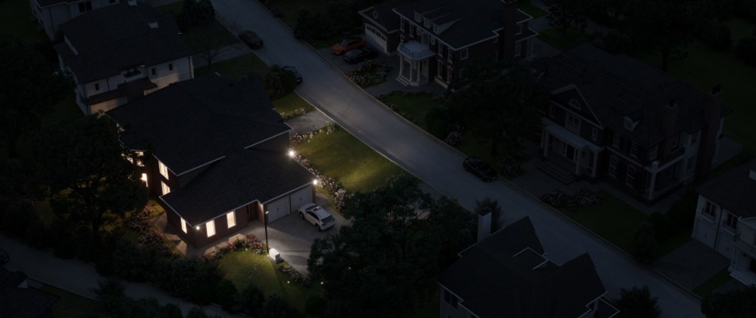 An aerial view of a house on the left with lights on at night