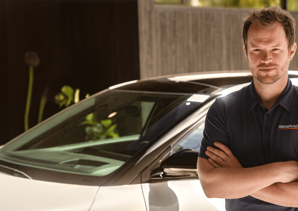 Generac technician standing next to an electric vehicle