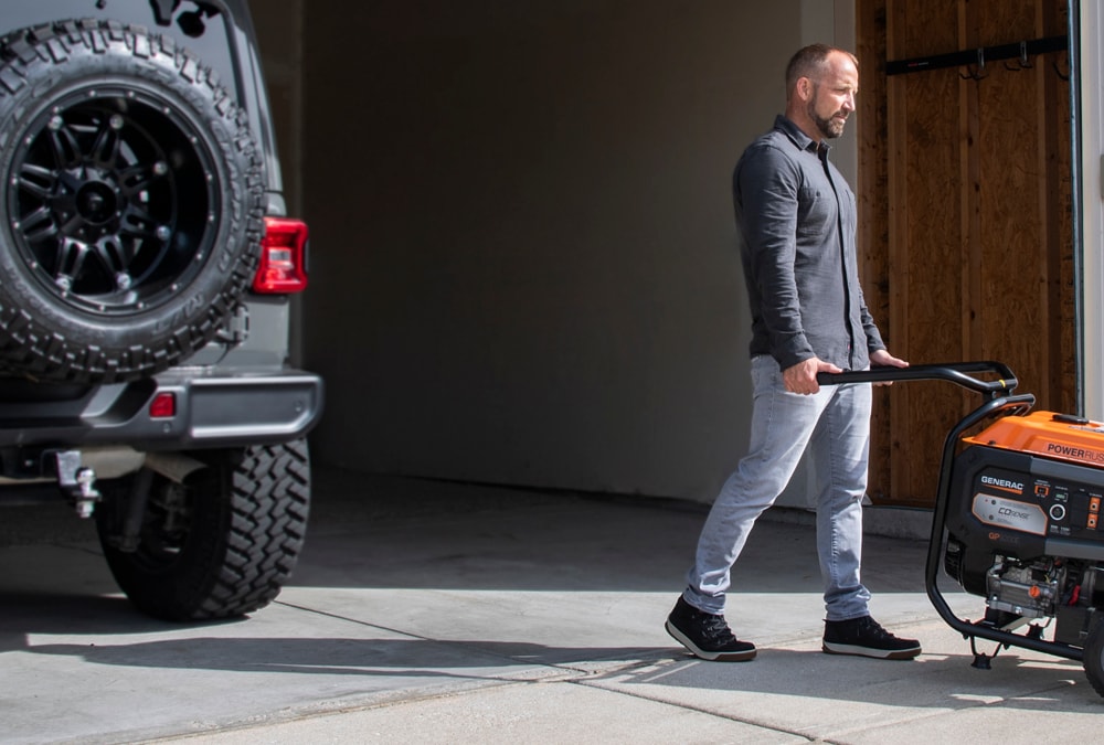 Person wheeling a Generac portable generator out of a garage