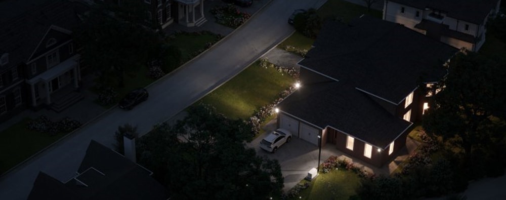 An aerial view of a house on the right with lights on at night