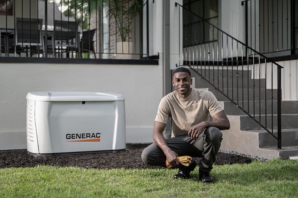 A generac installer smiling next to a newly installed generator
