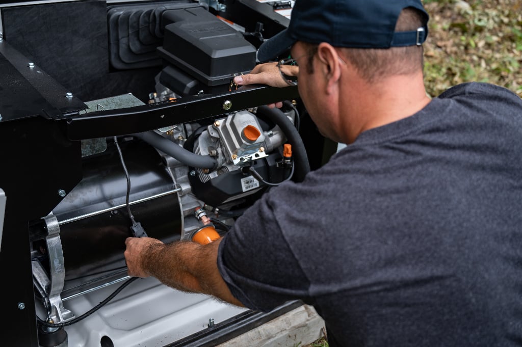 A generator with the lid open and a generac installer installing it