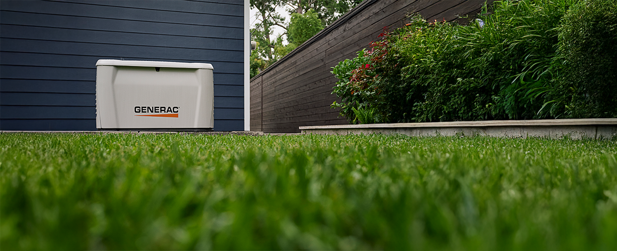 a generac home generator outside a home with a worms eye of grass.