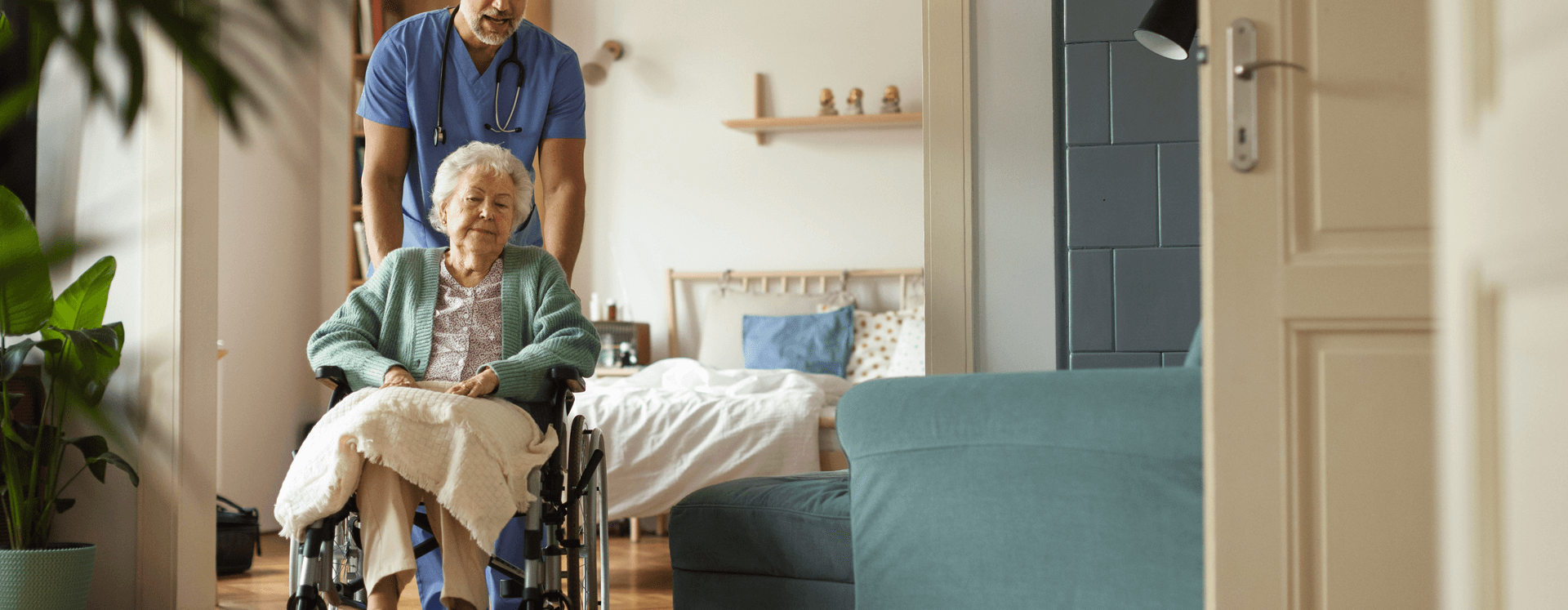 Male nurse pushing a patient in a wheelchair in a nursing home.