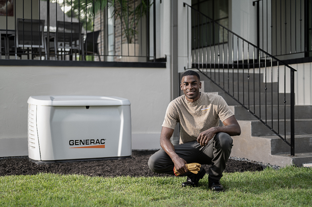 A generac installer smiling next to a newly installed generator