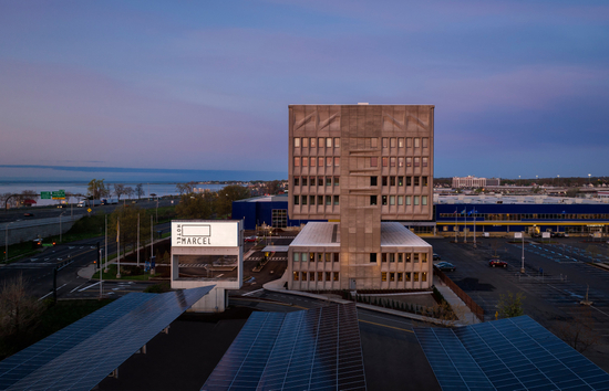 Image of Hotel Marcel at dusk with costline in the background and lit hotel sign.