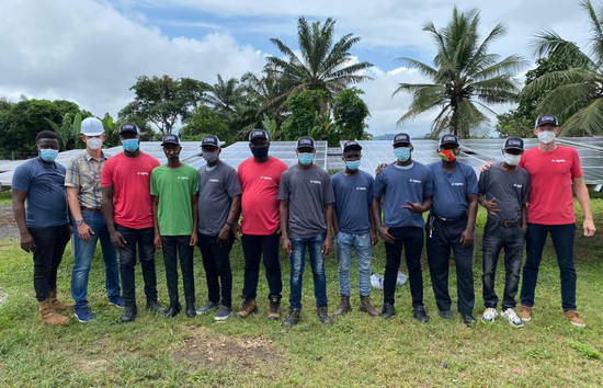Team of local technicians and project leaders in front of a solar array in Totota, Liberia, celebrating the launch of the community microgrid.