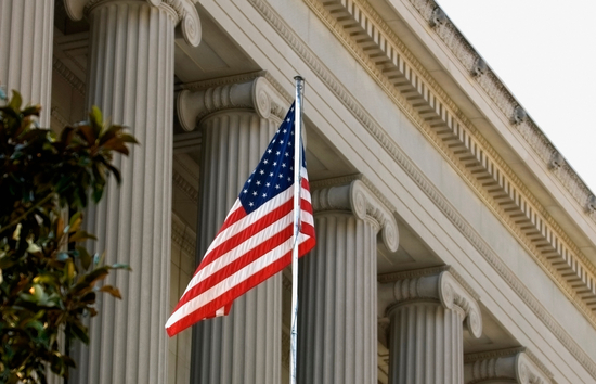 American flag in front of a government building representing Generac Sourcewell approved cooperative purchasing contracts for industrial power generation, mobile equipment, and grounds maintenance