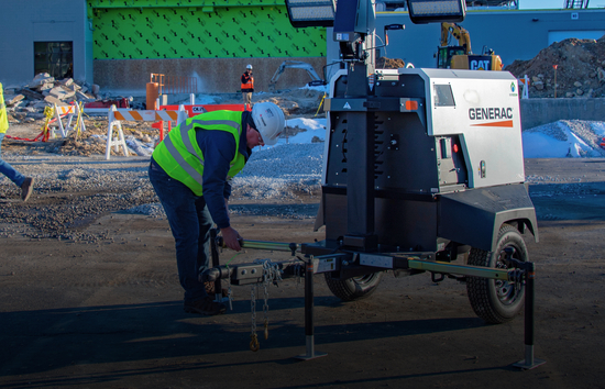 Technician securing mobile light tower at a construction site showing the value of having all Generac Light Tower manuals accessible for service, parts, and maintenance documentation