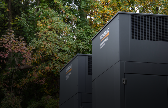 Two Generac Industrial Energy generators installed in a wooded setting, representing Generac’s customized modular design process for industrial backup power solutions.