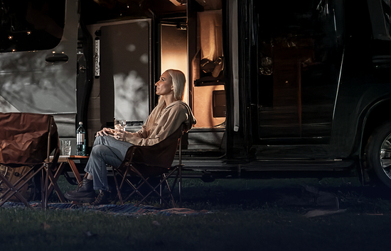 Woman sitting outside RV with portable generators at night