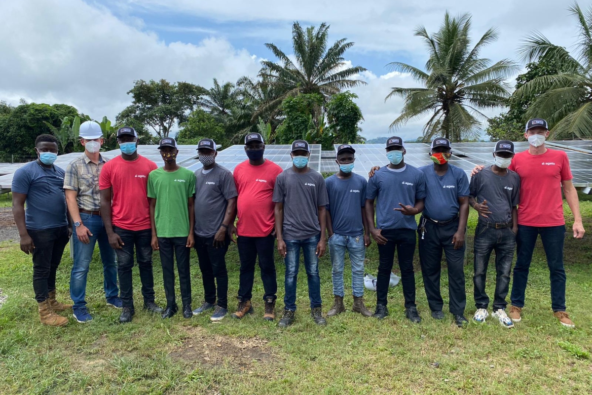 Team of local technicians and project leaders in front of a solar array in Totota, Liberia, celebrating the launch of the community microgrid.