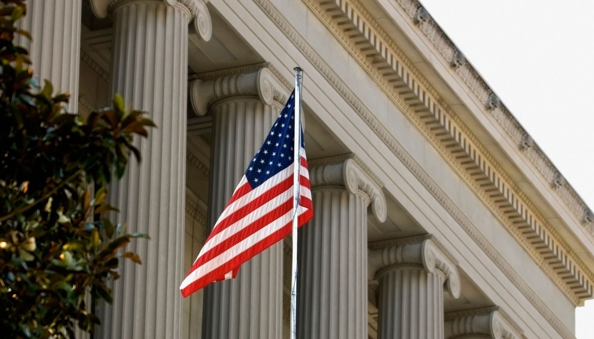 American flag in front of a government building representing Generac Sourcewell approved cooperative purchasing contracts for industrial power generation, mobile equipment, and grounds maintenance