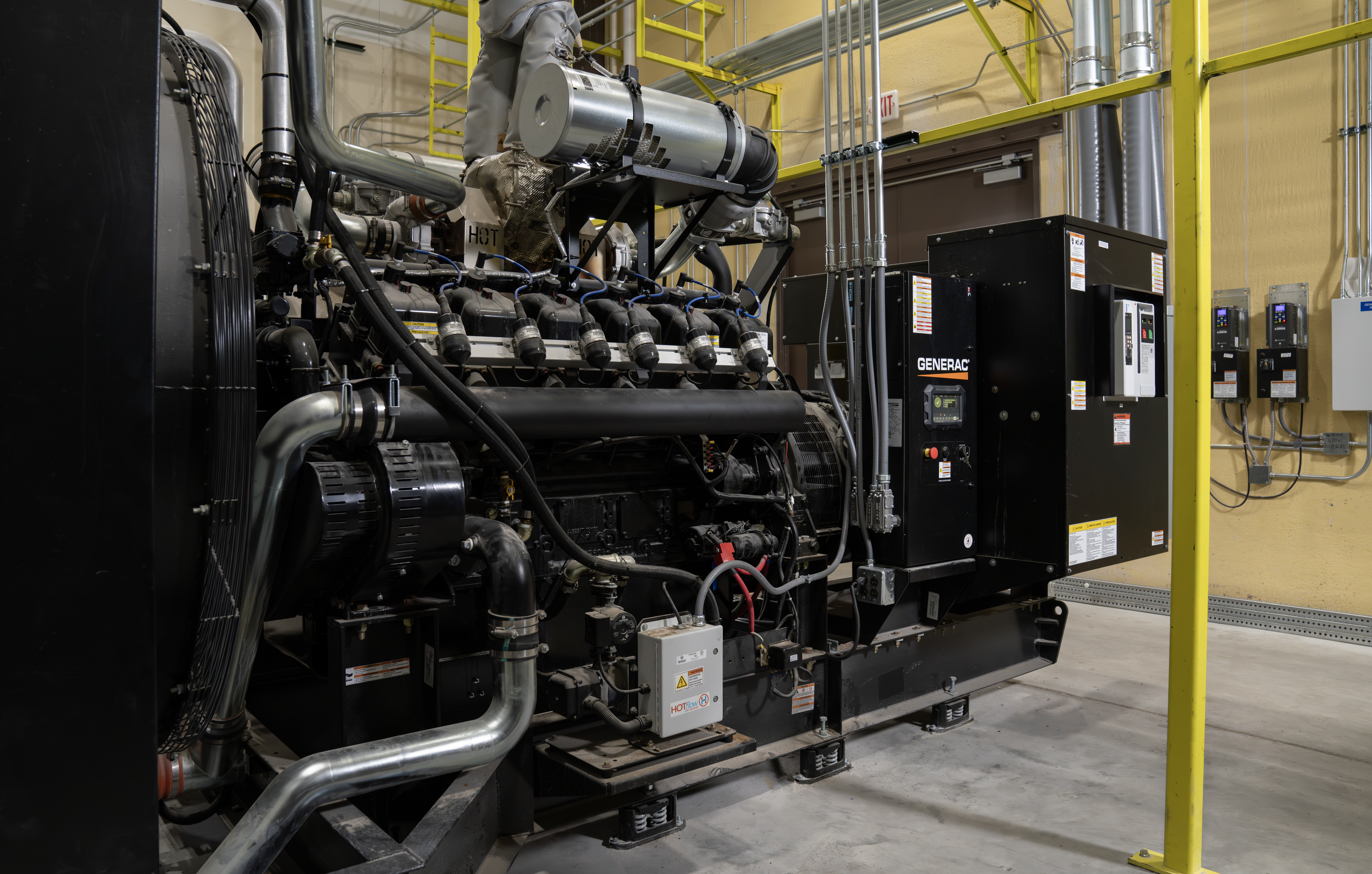 A large black commercial generator featuring a Generac logo sits inside a facility 