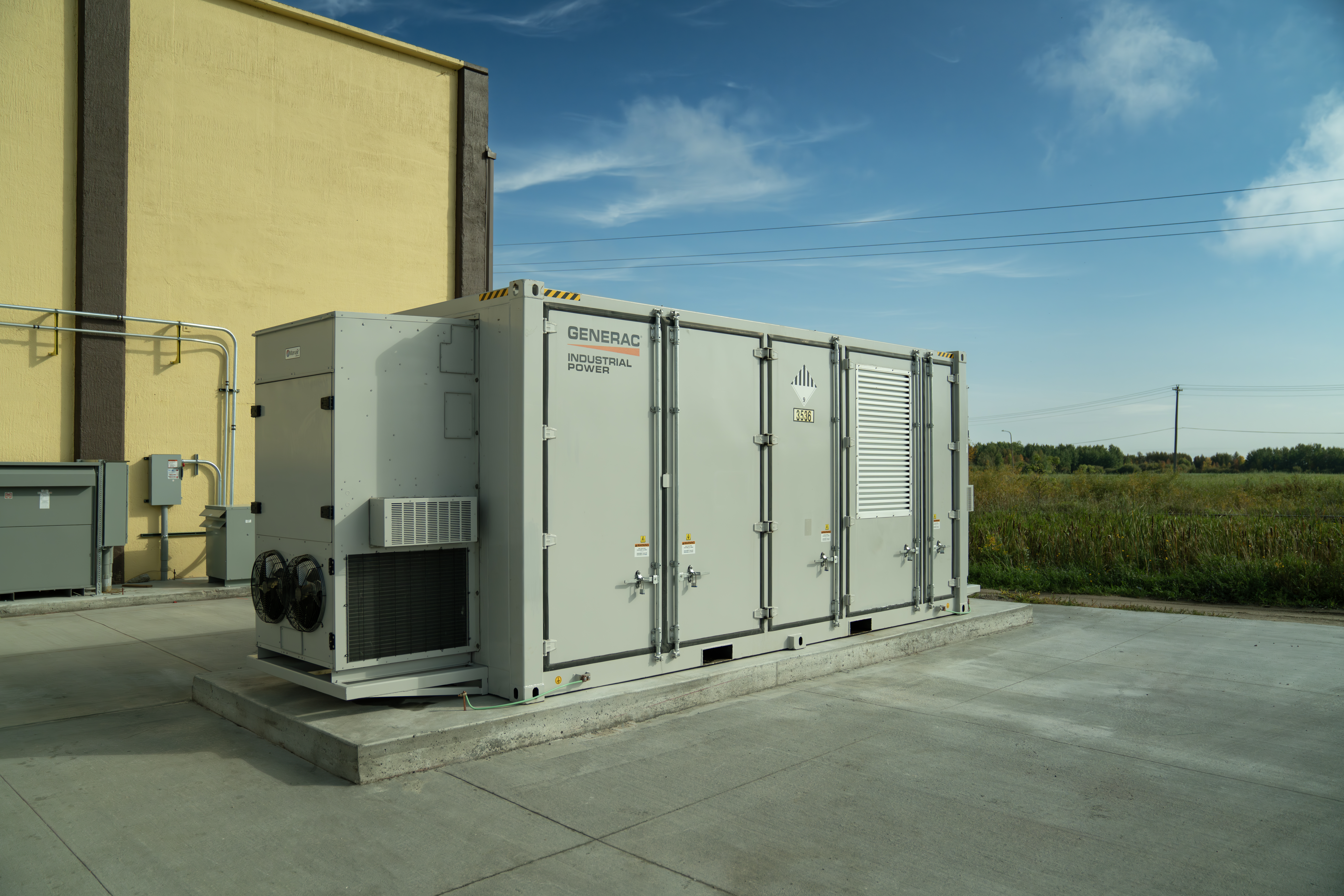  A large, gray, Generac Battery Energy Storage system sits outside a manufacturing facility