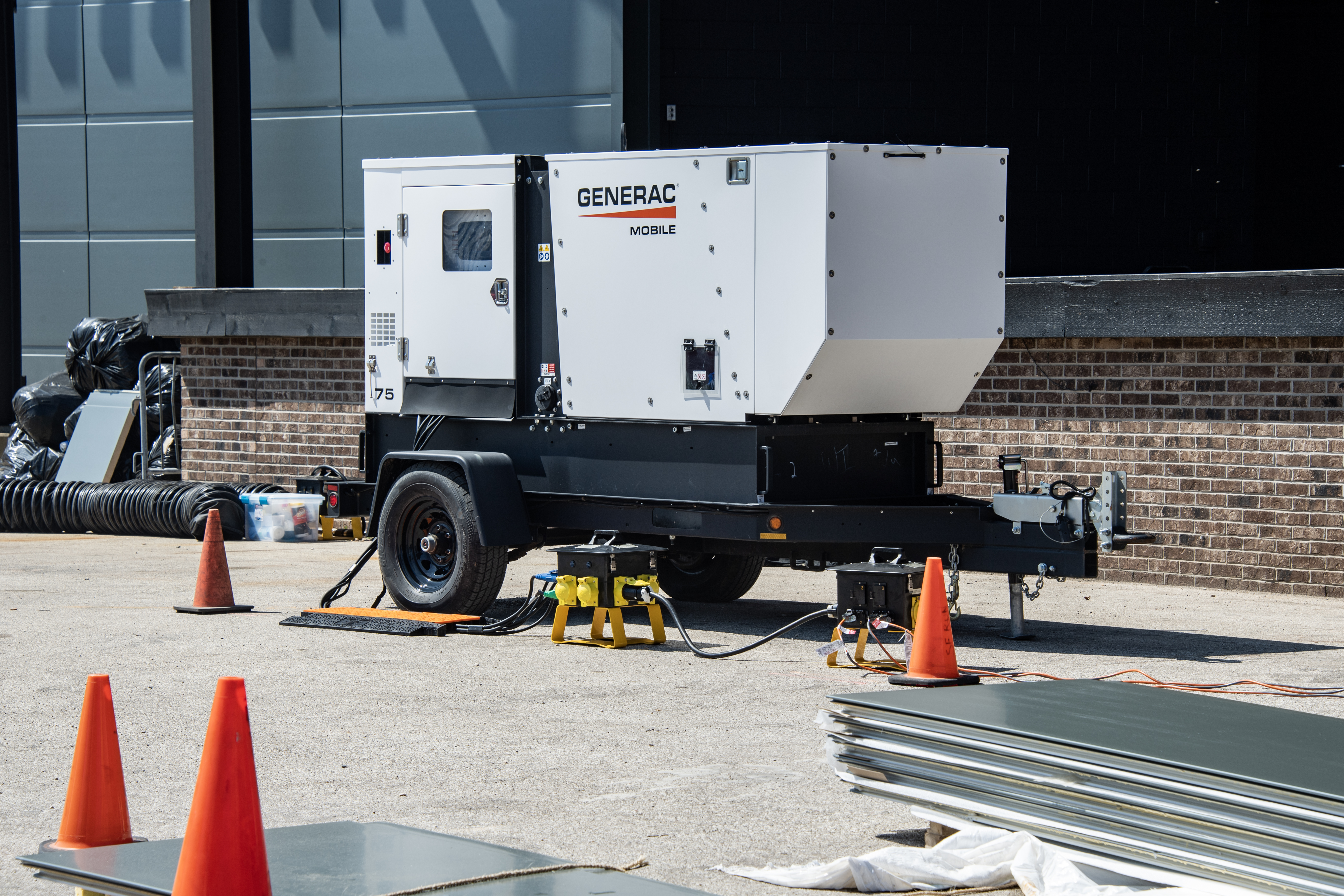  A white Generac mobile generator on wheels sits at a construction site