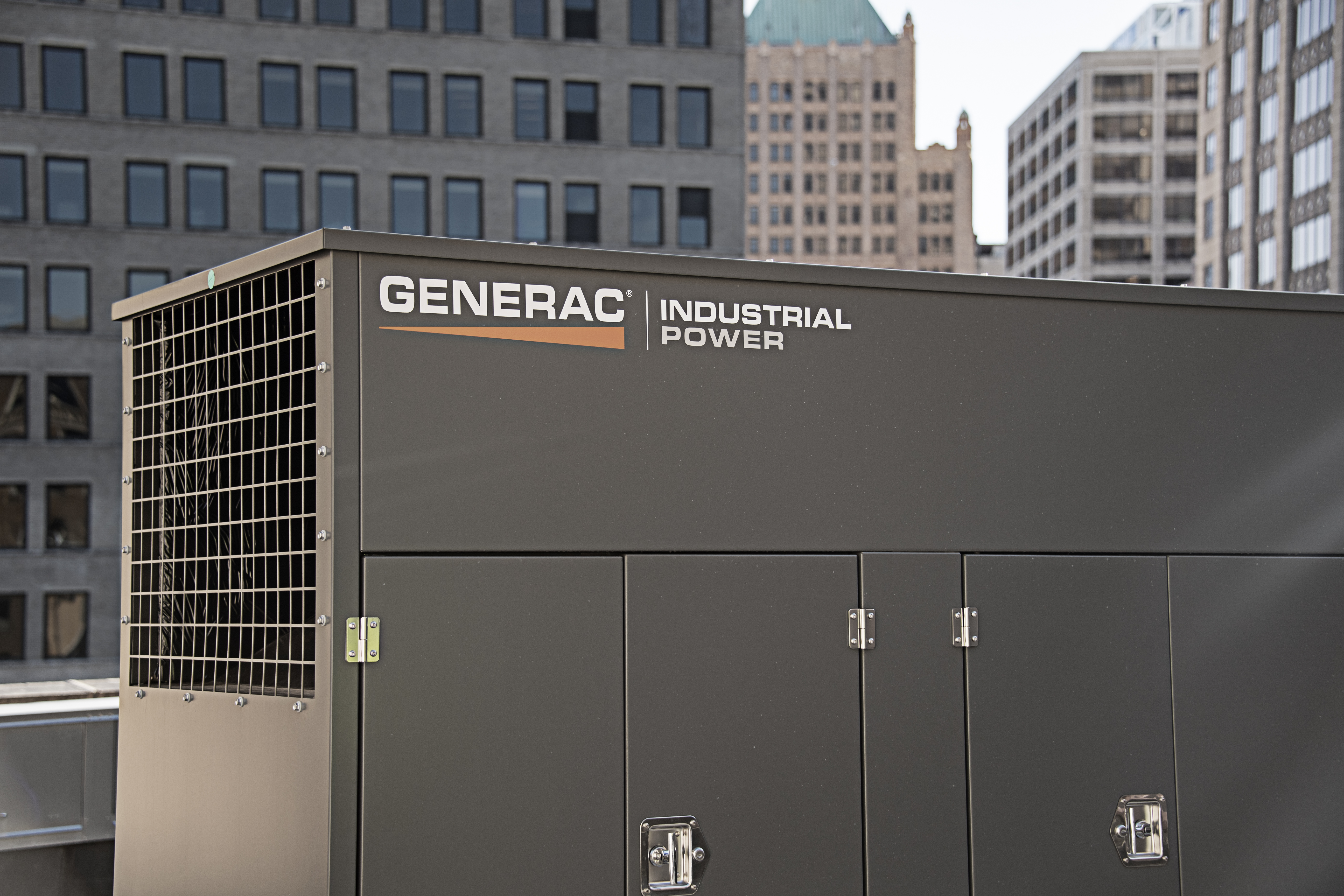A dark gray generator on a rooftop features the Generac logo