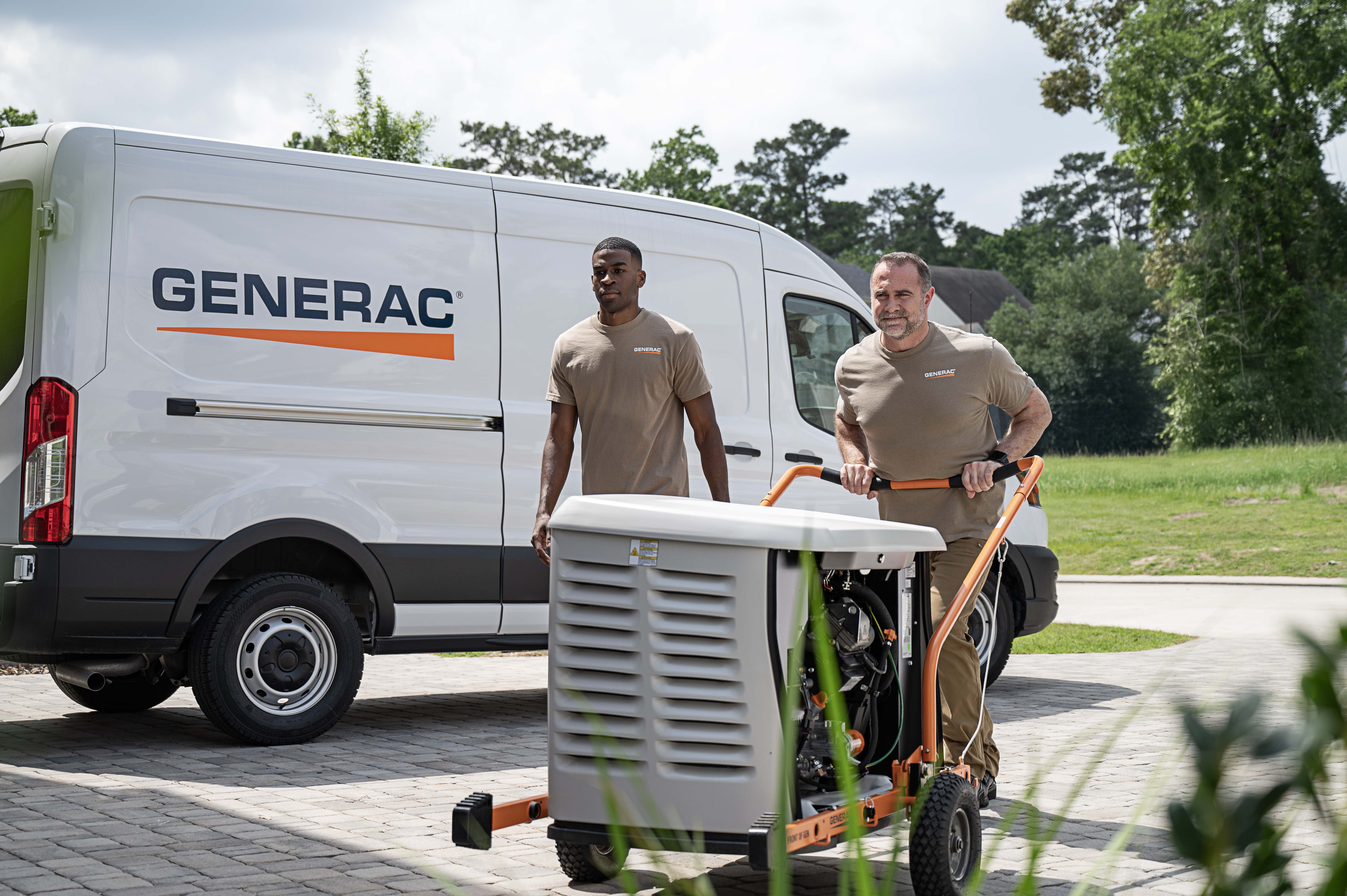 Two technicians push a Generac home standby generator on a cart