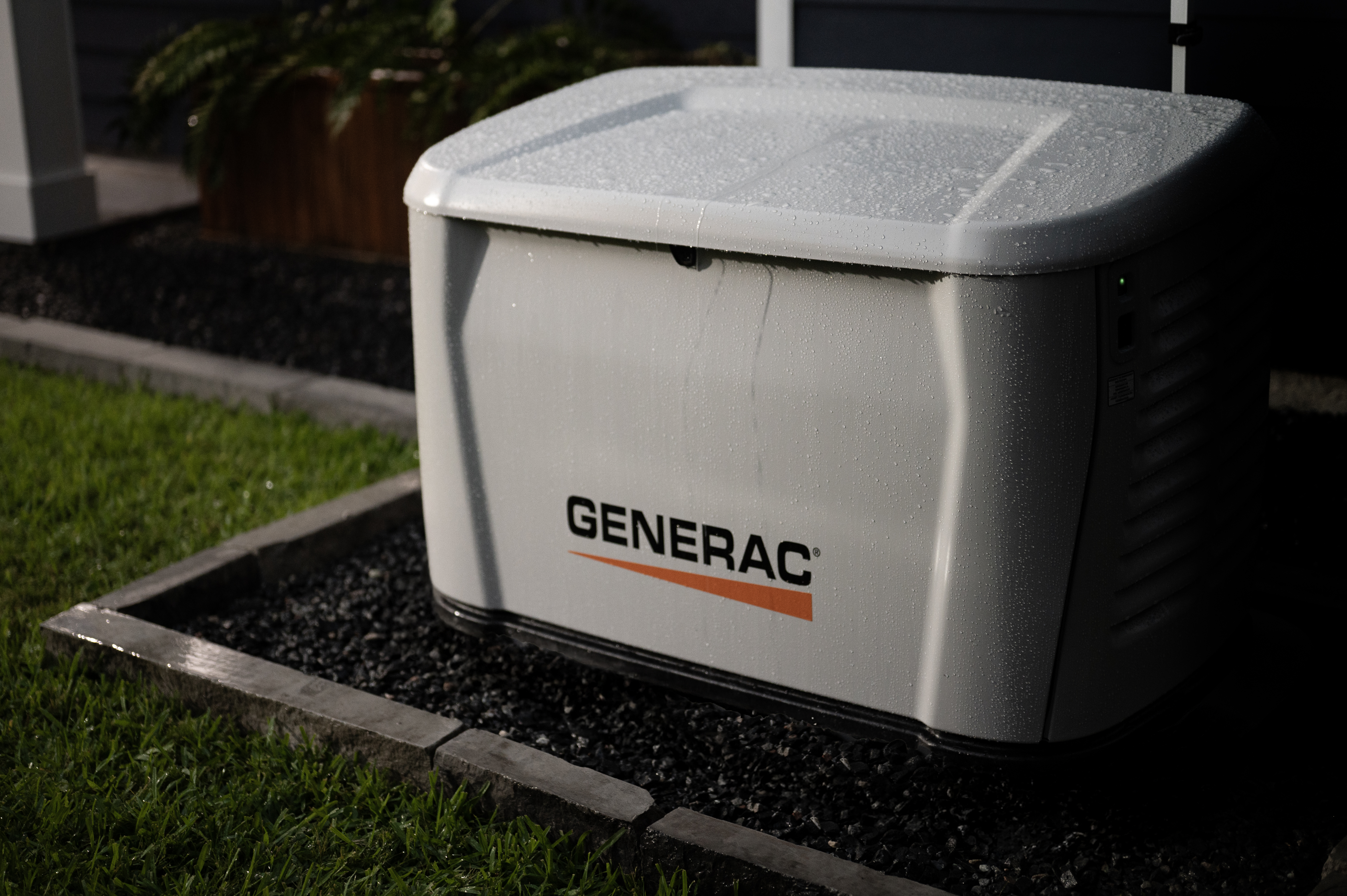  Generac home standby generator sits in a garden bed at night