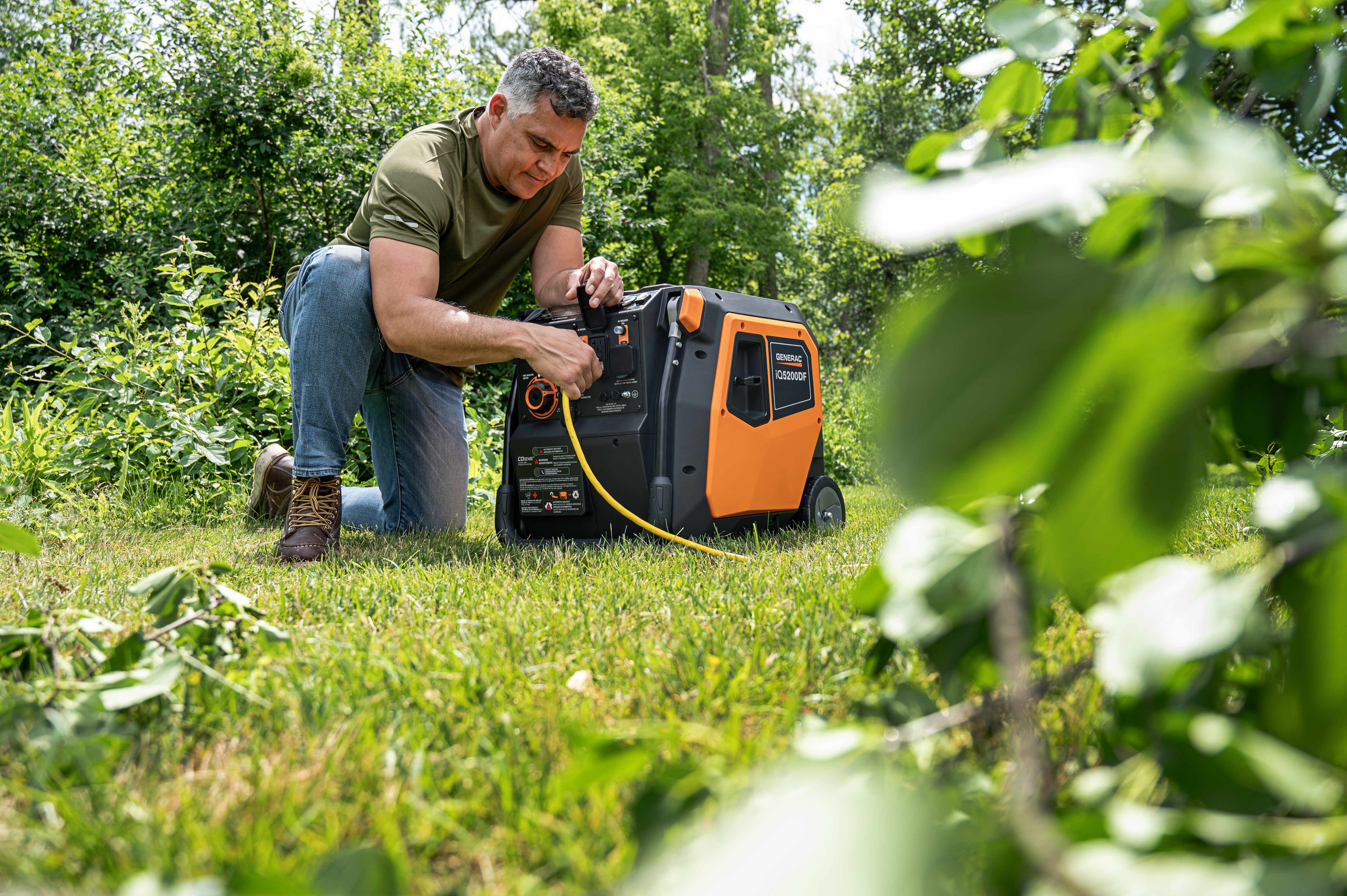A man plugs a power cord into a black and orange Generac power station