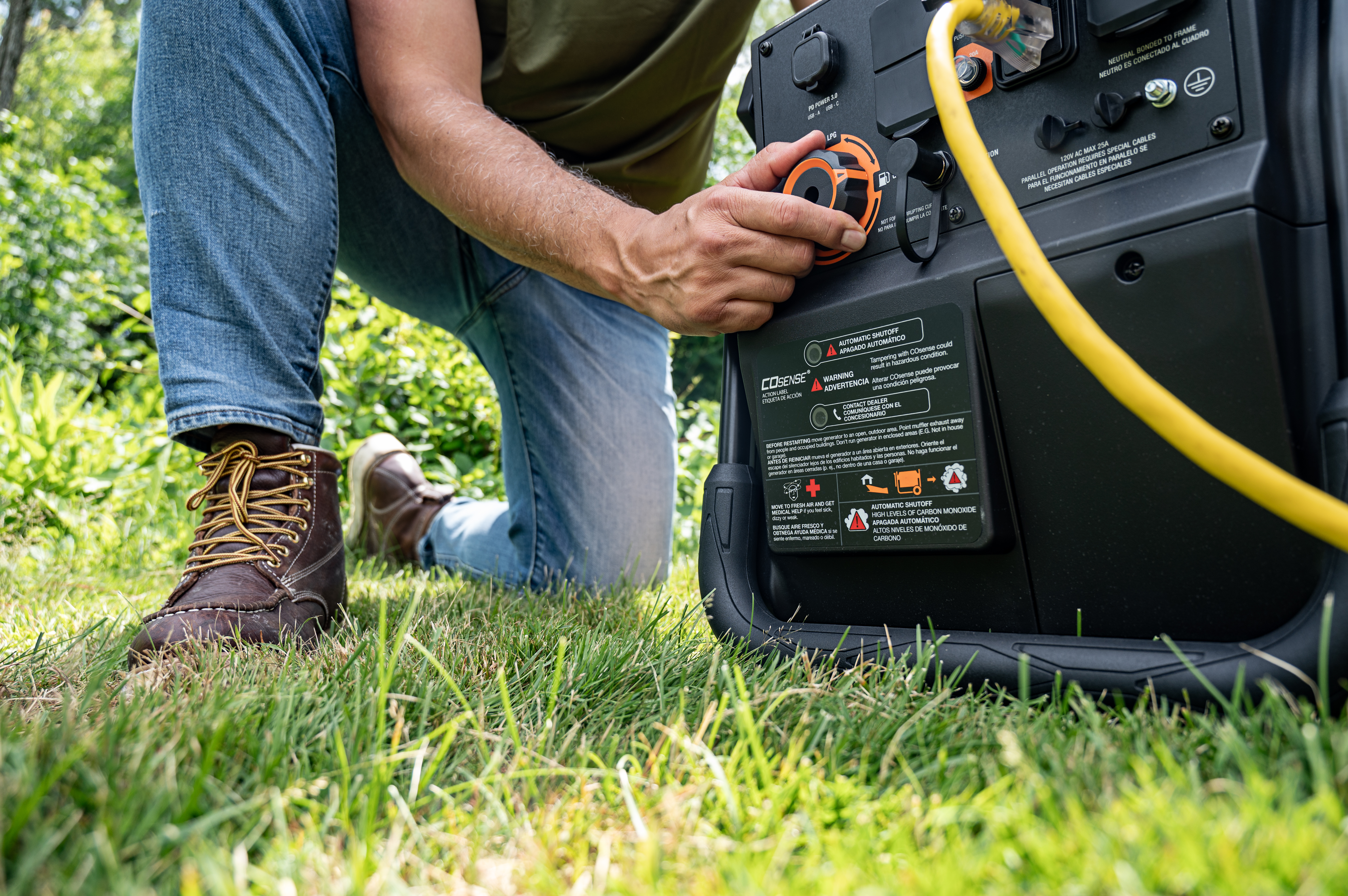  A man turns a knob on a black and orange Generac power station