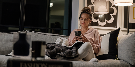 girl smiling down at phone in the dark with a lamp on 
