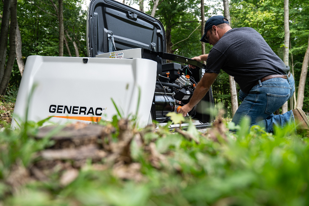 A generac home generator being installed with the hood lifted up and front end taken off to see the innards of the generator.