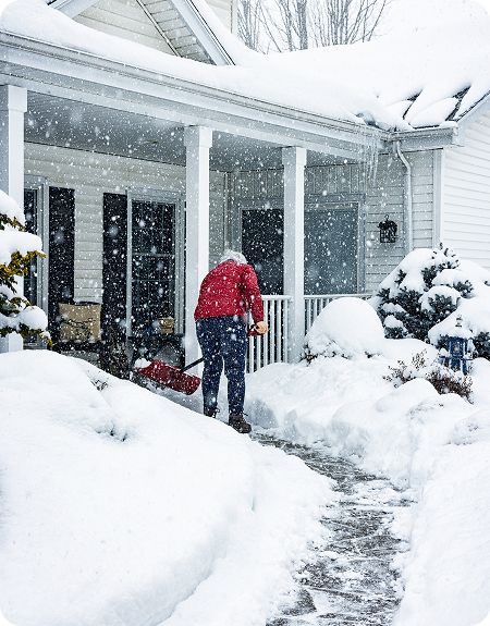 Person clearing snow outside a home during a winter storm