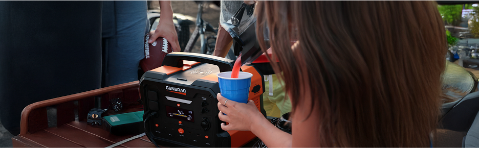 Woman using a Generac portable power station to blend drinks at a tailgate