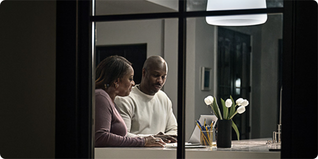 A couple working on a laptop seen through a window